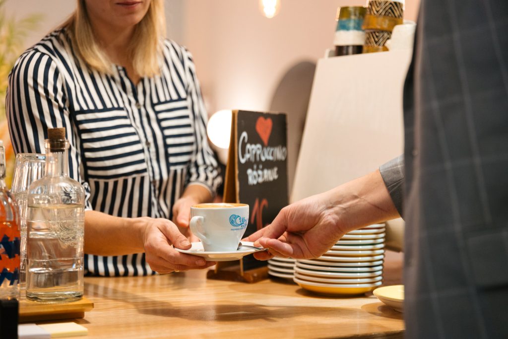 Podanie cappuccino gościowi przy barze kawiarni