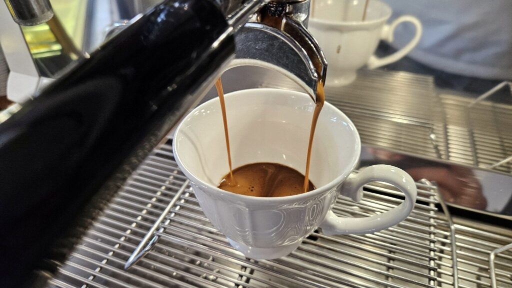 Espresso płynące dwoma strumieniami z kolby ekspresu do filiżanki