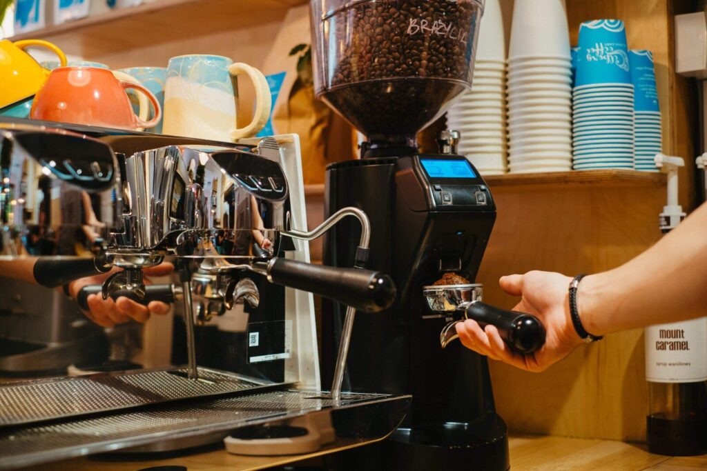 Barista mieli kawę do kolby w widełkach młynka przy ekspresie kolbowym w kawiarni